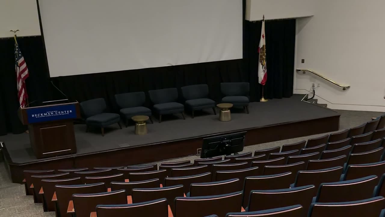 The empty auditorium, stage and screen above rows of fixed seats.